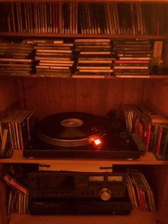 a record player is sitting on top of a shelf full of cd's and cds