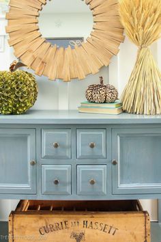 an old dresser is painted blue and has a decorative mirror above it