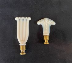 two white and gold vases sitting next to each other on a black table top