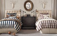 two beds in a room with antlers on the wall and mirrors above them,