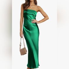 a woman in a green dress is holding a handbag and posing for the camera