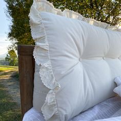 a white pillow sitting on top of a bed next to a wooden post and tree