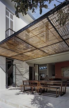 an outdoor dining area with wooden tables and benches under a bamboo covering over the table