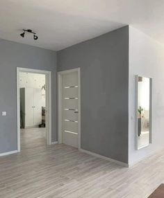 an empty room with two mirrors on the wall and one door open to another room