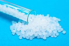 small white beads spilling out of a glass tube on a blue background stock photo 549782