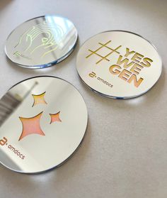 three metal coasters with different designs on them