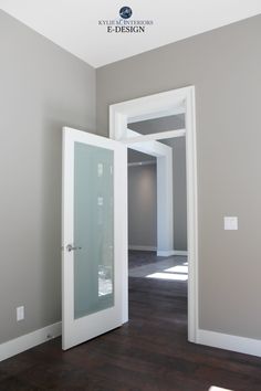 an empty room with white doors and wood flooring, in the middle of a gray wall