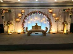 a stage set up for a wedding ceremony with flowers and candles on the sidelines