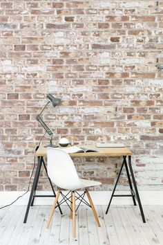 a desk with a lamp on it next to a brick wall