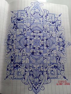 a notebook with an intricate design in blue ink on top of lined paper next to a pen