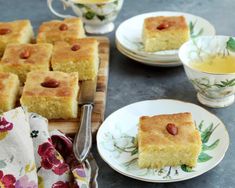 several pieces of cake sitting on plates next to cups and saucers with spoons