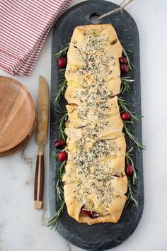 an oval platter filled with bread, cranberries and rosemary sprigs