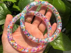 two bracelets that are sitting on top of each other in front of some plants