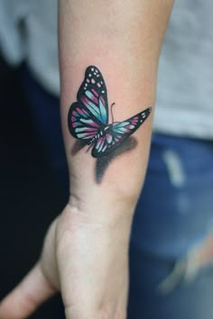 a woman's hand with a butterfly tattoo on her left wrist and the other arm