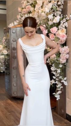 a woman in a white dress standing next to flowers