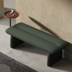 a green bench sitting next to a wall