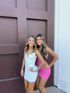 two beautiful young women standing next to each other in front of a garage door with their arms around each other