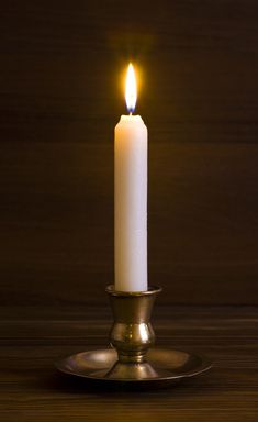 a lit candle sitting on top of a metal plate