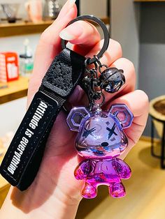 a person holding a keychain with a bear shaped object in it's hand