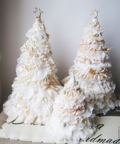 two white christmas trees sitting on top of a table