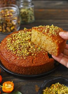 a person holding a piece of cake with pistachio toppings on it, in front of some small bowls