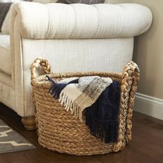 a basket sitting on top of a wooden floor next to a white couch and chair