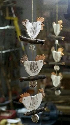 three bird ornaments hanging from a branch in front of a glass window with the reflection of another bird on it