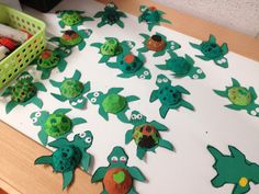 a table topped with lots of green paper cut out of sea animals and turtle heads