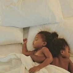 two children are laying in bed with white sheets