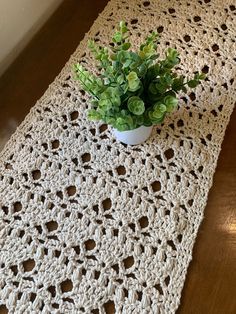 a crocheted table runner with a potted plant on top