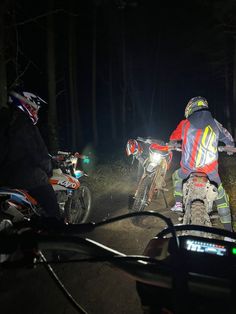 two motorcyclists riding in the woods at night