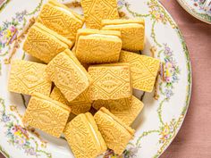 some yellow cookies are on a plate with pink table cloth and plates full of them