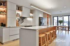 a kitchen with an island and bar stools in front of the counter top area