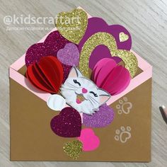 a close up of a card with a cat and hearts in the envelope on a table