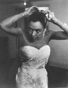 a black and white photo of a woman adjusting her hair