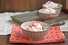 two bowls filled with whipped cream on top of a red and white place mat next to a tray