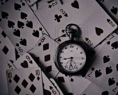 a pocket watch surrounded by playing cards