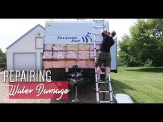 a man standing on top of a ladder next to a trailer filled with water damage