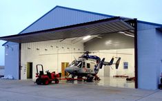 a helicopter is parked in front of a hangar