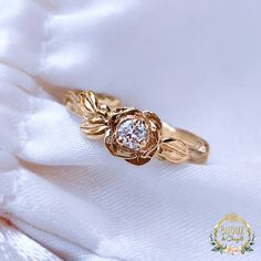 a close up of a ring on a white cloth with a diamond in the center