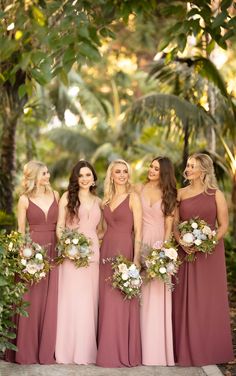 a group of women standing next to each other in long dresses with flowers on them