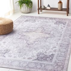 a large rug with an ornate design on the floor in front of a table and potted plant