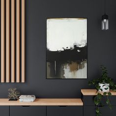 a black and white painting hangs on the wall next to a wooden shelf with books