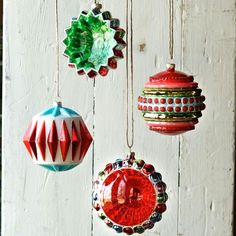 christmas ornaments hanging from strings on a white wooden wall with red, green and blue decorations