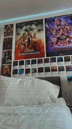 a bed with white sheets and posters on the wall