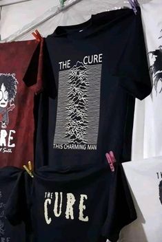 some t - shirts are hanging up on the wall in front of other clothing items