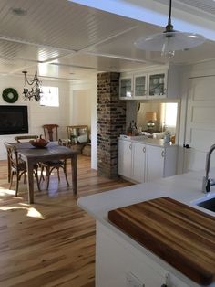 an open kitchen and dining room with wood flooring, white walls, and ceiling fan