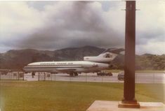 an airplane is parked on the tarmac with mountains in the background