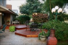 a deck with chairs and tables surrounded by greenery