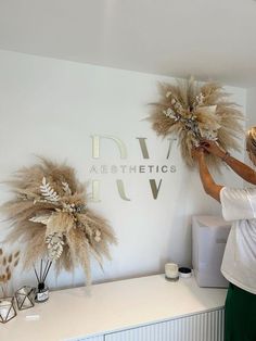 a woman standing in front of a white wall with two large feathers on top of it